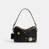Bolso bandolera Dakota del 10.º aniversario de Rexy en piel desgastada con estampado de pegatinas