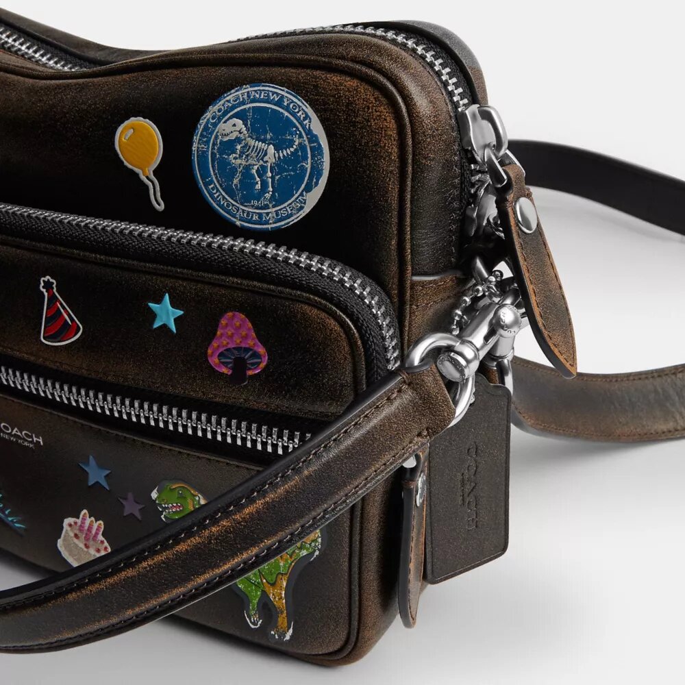 Bolso bandolera Dakota del 10.º aniversario de Rexy en piel desgastada con estampado de pegatinas