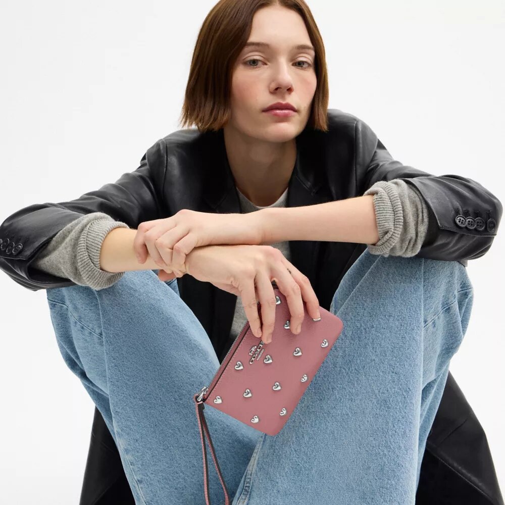 Bolso de pulsera con cremallera en la esquina y remaches en forma de corazón