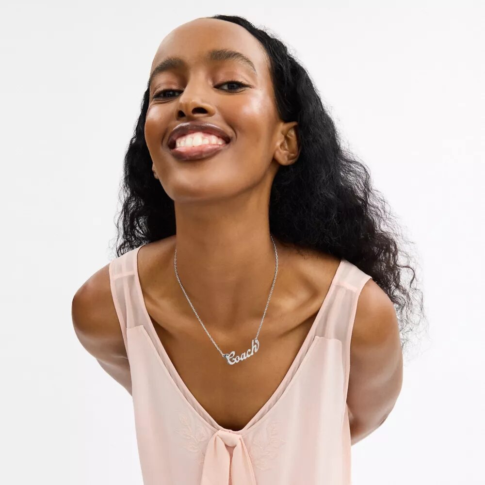 Collar con placa con el nombre en letra «Coach Script»